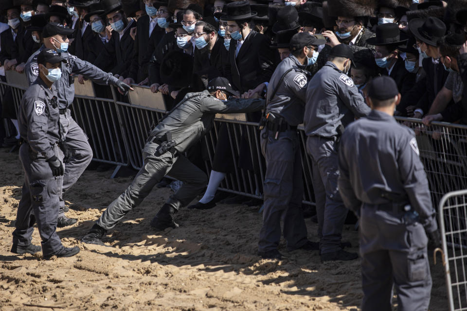 Israeli police try to control a crowd of mourners during the funeral of Rabbi Mordechai Leifer, the latest in a string of clashes between security forces and ultra-Orthodox Jews violating a national coronavirus lockdown order, in the port city of Ashdod, Israel, Monday, Oct. 5, 2020. The late rabbi, who had been the spiritual leader of a small ultra-Orthodox community founded a century ago in the U.S. city of Pittsburgh, died Sunday after a long bout with COVID-19. (AP Photo/Tsafrir Abayov)