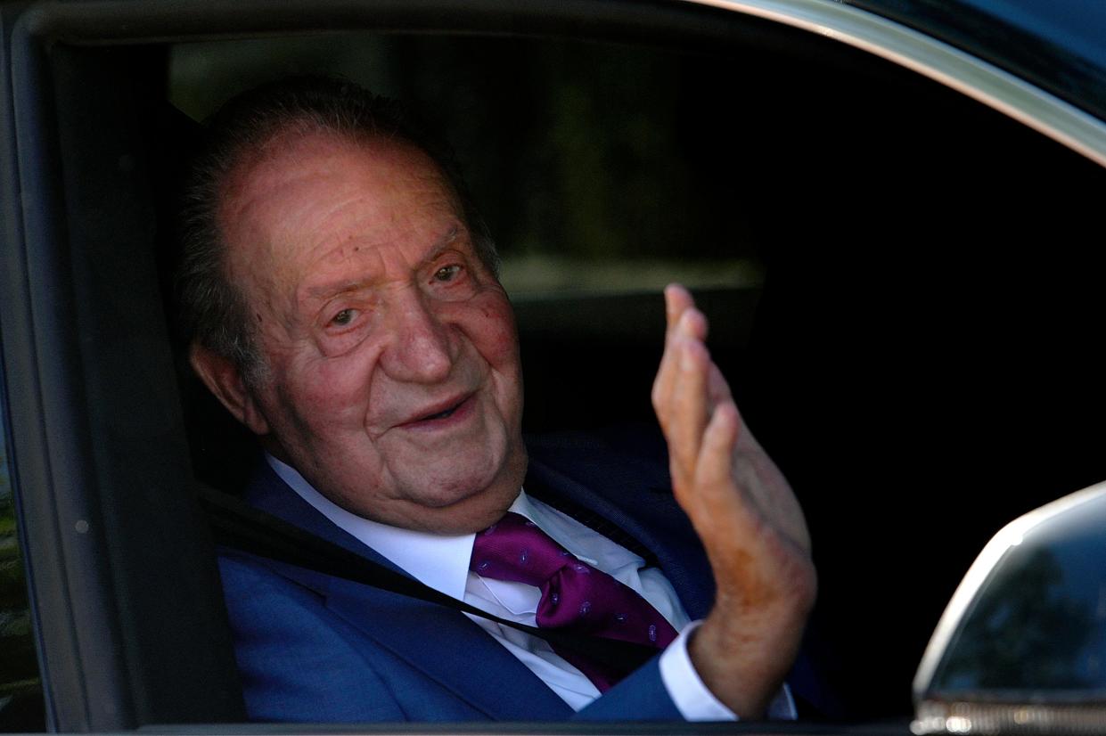 TOPSHOT - Former king Juan Carlos I of Spain, waves from a car as he arrives at La Zarzuela palace in Madrid, on May 23, 2022, to meet with his son, King Felipe VI of Spain. - Scandal-hit Spanish ex-king Juan Carlos I visited his son and current monarch Felipe VI in Madrid today, during a controversial visit home after two years in self-imposed exile. The meeting concluded the former king's first trip back to Spain since he went into exile in the UAE in August 2020, following a string of financial scandals that did irreparable damage to his reputation. (Photo by OSCAR DEL POZO / AFP) (Photo by OSCAR DEL POZO/AFP via Getty Images)