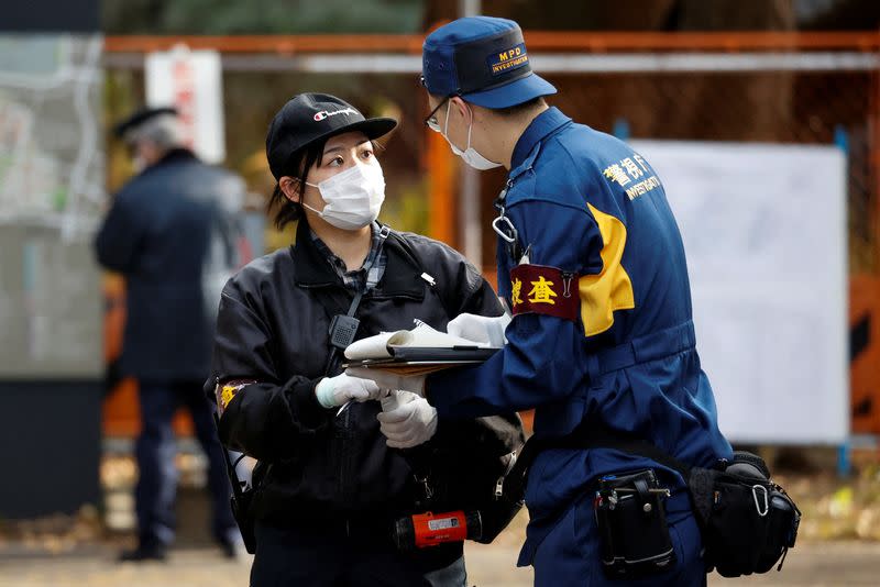 A police investigator speaks to another person at the site where a stabbing incident happened at an entrance gate of Tokyo University in Tokyo