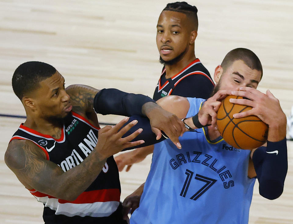 Jonas Valanciunas de los Grizzlies de Memphis y Damian Lillard de los Trail Blazers de Portland pelean por el balón en la segunda mitad del juego del sábado 15 de agosto del 2020 en Lake Buena Vista, Florida. (Kevin C. Cox/Pool Photo via AP)