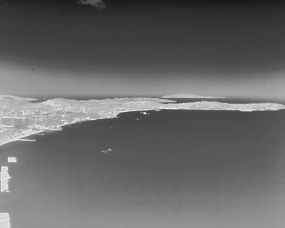 This photo depicting, through thermal imaging camera, a long-range drone, center, patrols over Kavouri beach and nearby woodland, in southern Athens, Greece, Thursday, Aug. 17, 2023. Greece is plagued by hundreds of wildfires each summer. To protect their area from potentially deadly blazes, a group of residents from a suburb in northern Athens have joined forces to hire a company using long-range drones equipped with thermal imaging cameras and a sophisticated early warning system to catch fires before they can spread. (AP Photo/Thanassis Stavrakis)