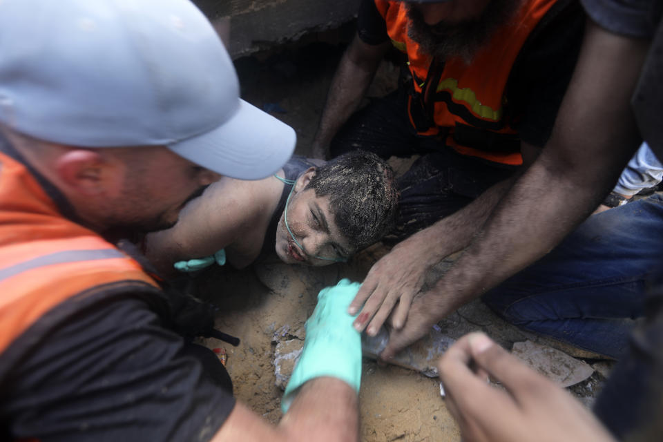 Palestinians try to rescue a boy from under the rubble of a destroyed building following an Israeli airstrike in Khan Younis refugee camp, southern Gaza Strip, Monday, Nov. 6, 2023. (AP Photo/Mohammed Dahman)