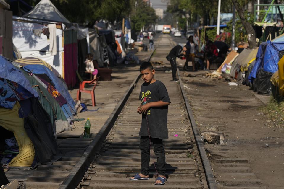 A young migrant from Venezuela plays with a spinning top on the railroad tracks lined by tents and makeshift shelters in Mexico City, Tuesday, March 26, 2024. (AP Photo/Fernando Llano)