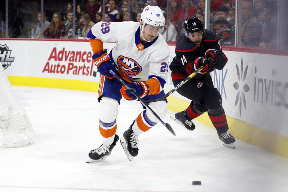 New York Islanders' Brock Nelson (29) moves the puck away from a charging Carolina Hurricanes' Justin Williams (14) during the second period of an NHL hockey game in Raleigh, N.C., Sunday, Jan. 19, 2020. (AP Photo/Karl B DeBlaker)