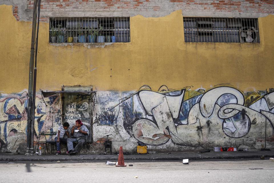 A mechanic takes a break in the Catia neighborhood of Caracas, Venezuela, Tuesday, April 19, 2022. Mechanics are increasingly busy as they try to coax a little more life out of aging vehicles in a country whose new car market collapsed and where few can afford to trade up for a better used one. (AP Photo/Matias Delacroix)