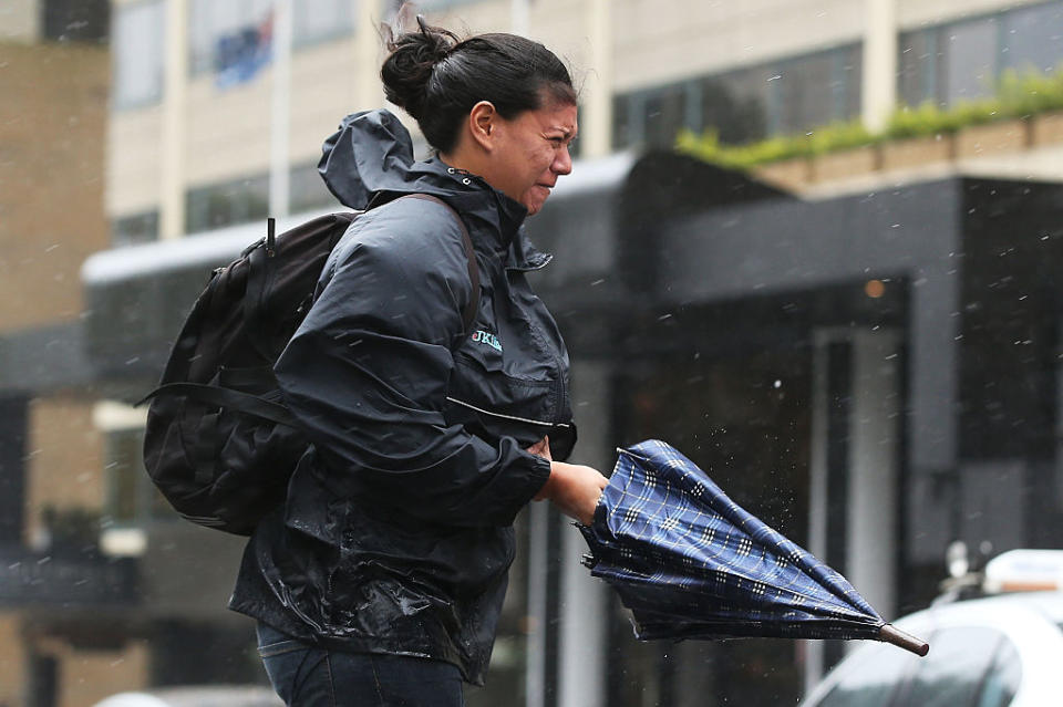 A woman walks through Sydney's CBD in heavy winds