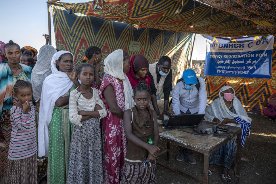 Tigray refugees who fled a conflict in the Ethiopia's Tigray region, wait to register their names for a convoy to transfer them to Umm Rakouba refugee camp, in Village 8, near the Lugdi border crossing, eastern Sudan, Tuesday, Dec. 8, 2020. Government officials are transferring all refugees from Village 8, temporarily hosting refugees to Umm Rakboua, the only official refugee camp. (AP Photo/Nariman El-Mofty)