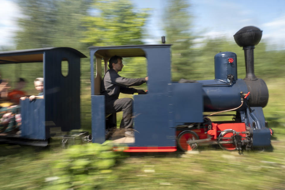 Sergei Terekhov drives a miniature steam train traveling along Pavel Chilin's personal railway in Ulyanovka village outside St. Petersburg, Russia, Sunday, July 19, 2020. It took Chilin more than 10 years to build a 350-meter-long mini-railway twisting through the grounds of his cottage home about 50 kilometers (some 30 miles) outside St. Petersburg, complete with various branches, dead ends, circuit loops, and even three bridges.(AP Photo/Dmitri Lovetsky)