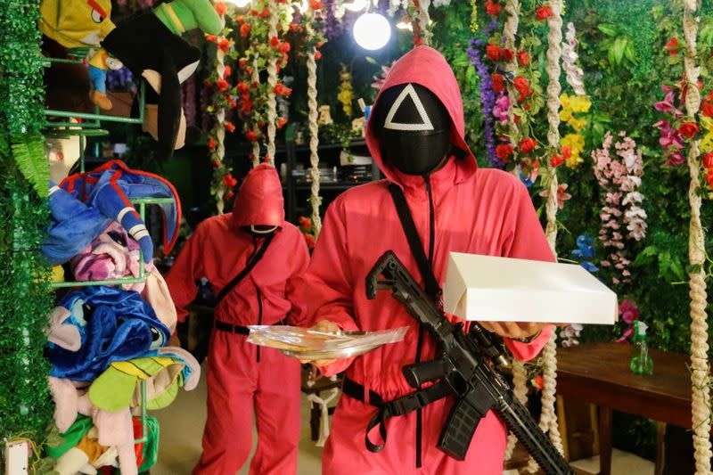 FILE PHOTO: Waiters wearing 'Squid Game' costumes carry trays with the honeycomb toffee at Strawberry Cafe in Jakarta