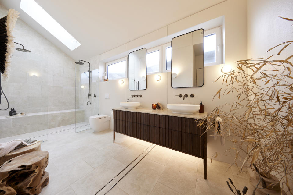 A wide shot of the ensuite with a plant on the right, the vanity in the centre and shower on the far left. 