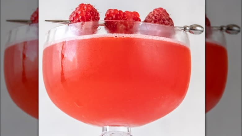 A Blinker cocktail garnished with a trio of raspberries