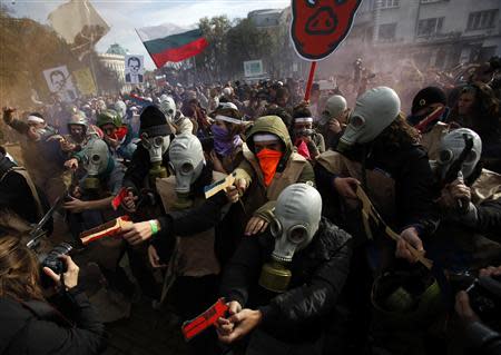 Protesting students wearing gas masks and carrying fake guns made of cardboard participate in a demonstration in front of the parliament in Sofia November 20, 2013. REUTERS/Stoyan Nenov