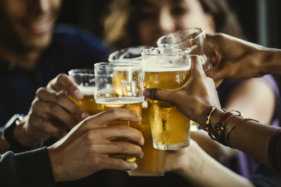 group of people clinking beer glasses together at a bar