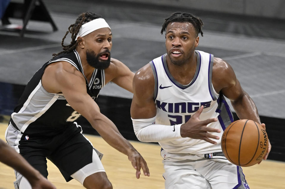 Sacramento Kings' Buddy Hield, right, drives around San Antonio Spurs' Patty Mills during the second half of an NBA basketball game, Wednesday, March 31, 2021, in San Antonio. (AP Photo/Darren Abate)