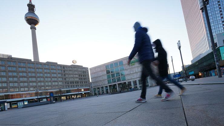 dpatopbilder - 22.03.2020, Berlin: Der Schriftzug «if you can read this - go home!» ist auf dem Pflaster auf dem Alexanderplatz zu lesen. Zwei Menschen gehen über den Platz. Foto: Jörg Carstensen/dpa +++ dpa-Bildfunk +++ Foto: dpa