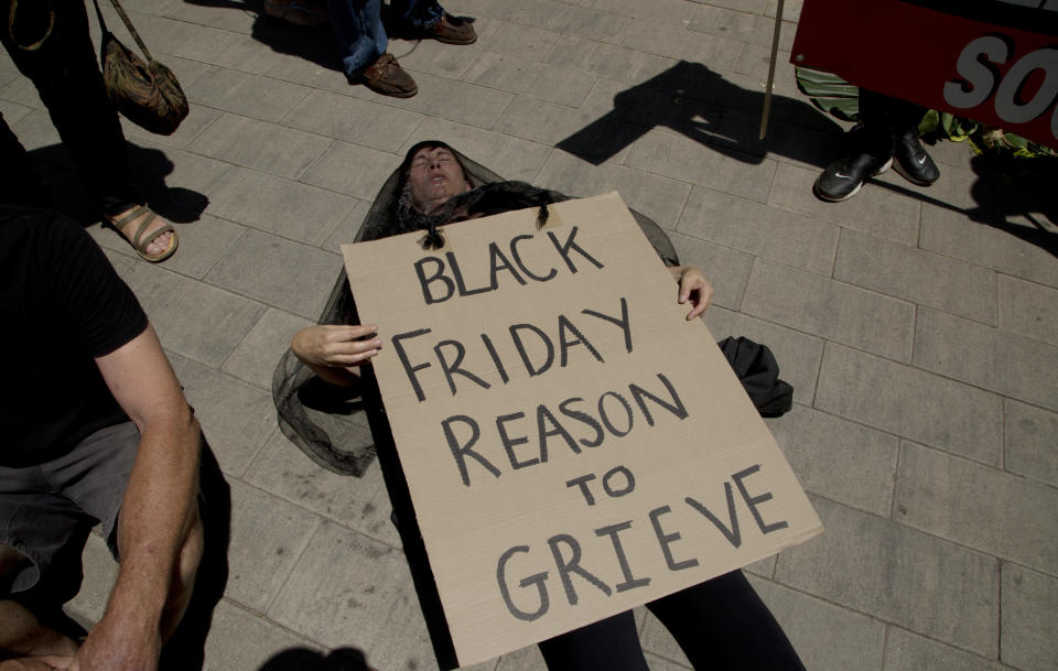 A demonstrator "plays dead" during climate change protest outside the Johannesburg Stock Exchange in Johannesburg Friday, Nov. 29, 2019. Environmentalists around the world are joining a global day of protests Friday, in a symbolic gesture to demand that governments act against climate change. (AP Photo/Denis Farrell)