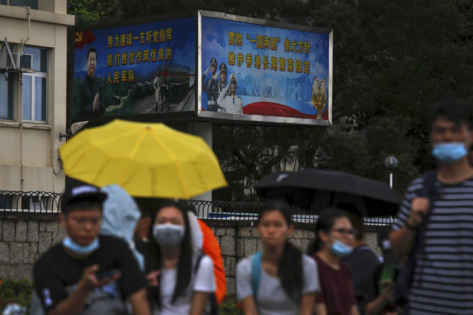 Protesters with umbrellas gather near billboards carrying a photo of Chinese President Xi Jinping and Chinese People's Liberation Army (PLA) near the Legislative Council as they continue to protest against the unpopular extradition bill in Hong Kong, Monday, June 17, 2019. (AP Photo/Kin Cheung)