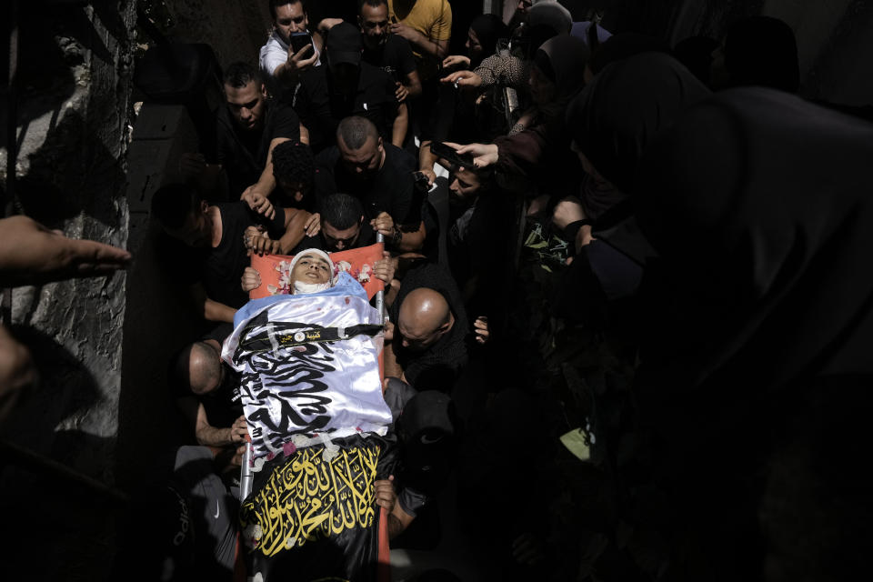 Mourners carry Ahmed Amouri, draped in Palestinian Islamic Jihad militant group flags, during his funeral after he was was killed in an Israeli military operation, in Jenin refugee camp in the West Bank city of Jenin, Friday, July 5, 2024. The Israeli military said Friday it was conducting counterterrorism activity that included an airstrike in the area of the West Bank city of Jenin. Palestinian authorities said five people were killed. (AP Photo/Majdi Mohammed)