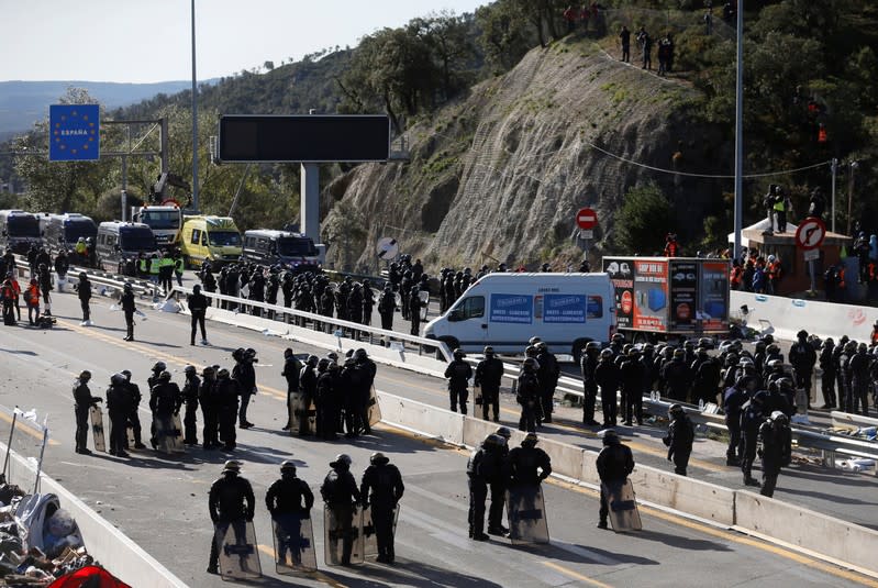 Police officers stand guard as members of Catalan protest group Democratic Tsunami gather at the AP-7 highway