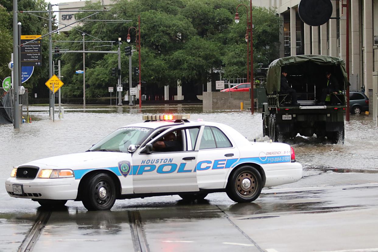 A Houston police officer blocks a flooded street as emergency services look for people stranded in flooded downtown Houston: THOMAS B. SHEA/AFP/Getty Images