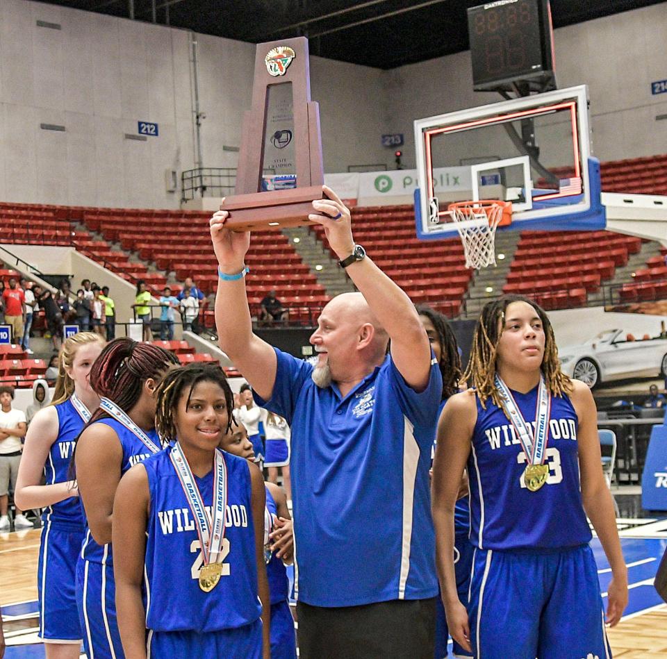 Wildwood girls basketball coach Richard Hampton holds up the championship trophy after Wildwood won the 2018 Class 1A state championship. It was the Wildcats' second straight state title.