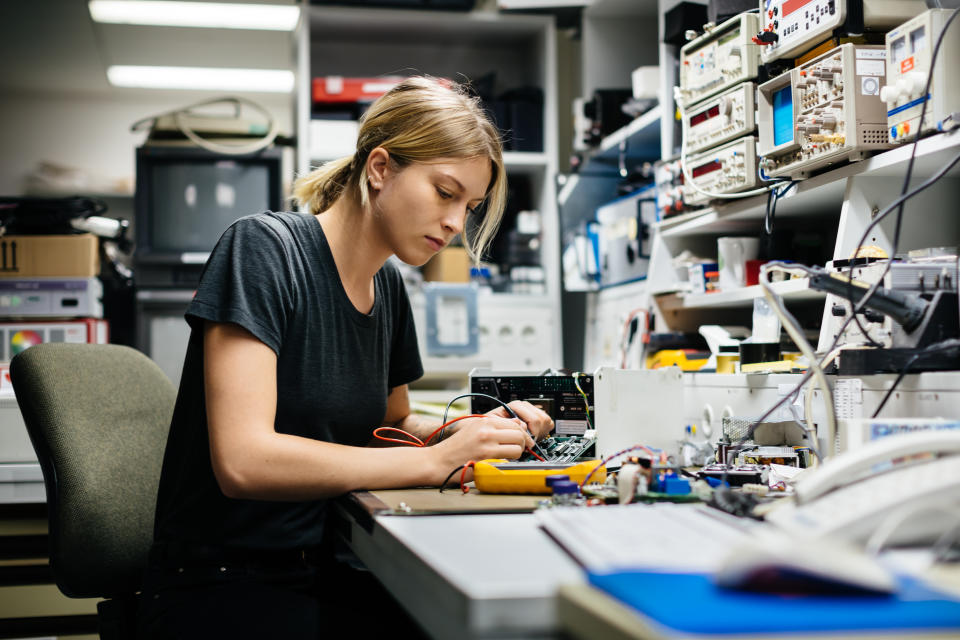 Young female engineer measuring voltage on a conductor board in her workshop