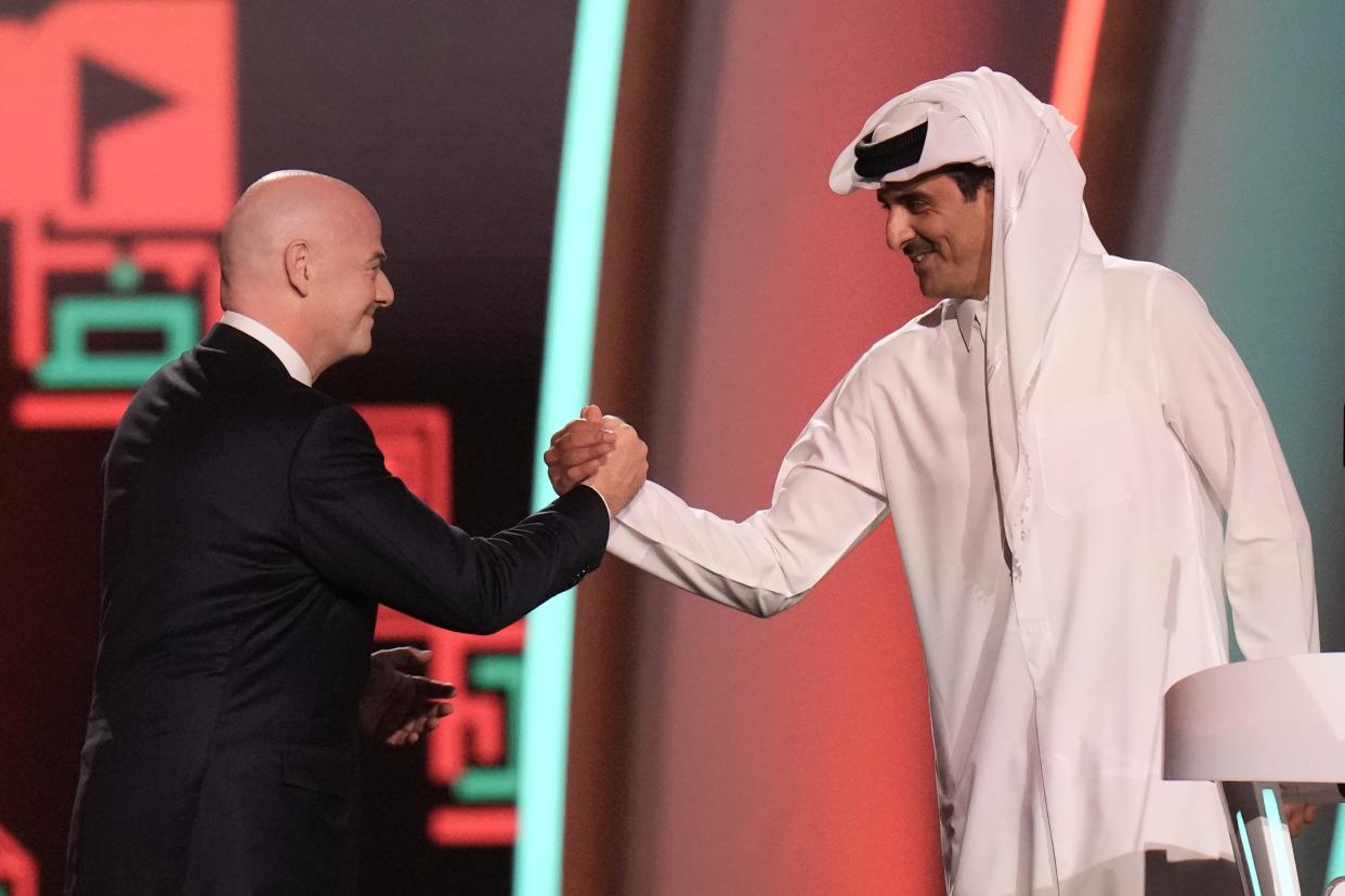 FILE - FIFA President Gianni Infantino, left, and Emir of Qatar Sheikh Tamim bin Hamad Al Thani shake hands before the 2022 soccer World Cup draw at the Doha Exhibition and Convention Center in Doha, Qatar, Friday, April 1, 2022. World Cup fans could bring political tensions to quiet Qatar. (AP Photo/Hassan Ammar, File)