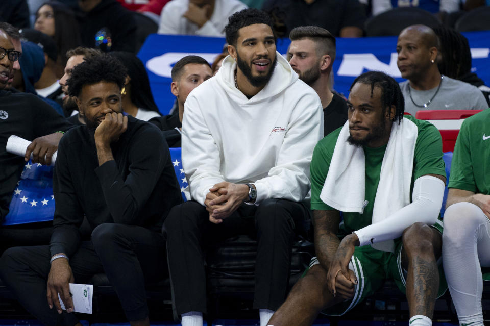 Boston Celtics' Jayson Tatum, center, watches from the bench with Jaylen Brown, left, and Jrue Holiday, right, during the second half of the team's preseason NBA basketball game against the Philadelphia 76ers, Wednesday, Oct. 11, 2023, in Philadelphia. (AP Photo/Chris Szagola)