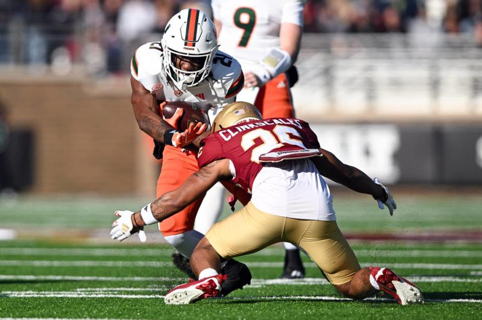 Nov 24, 2023; Chestnut Hill, Massachusetts, USA; Miami Hurricanes running back Henry Parrish Jr. (21) runs against Boston College Eagles defensive back CJ Clinkscales (26) during the first half at Alumni Stadium. Mandatory Credit: Brian Fluharty-USA TODAY Sports