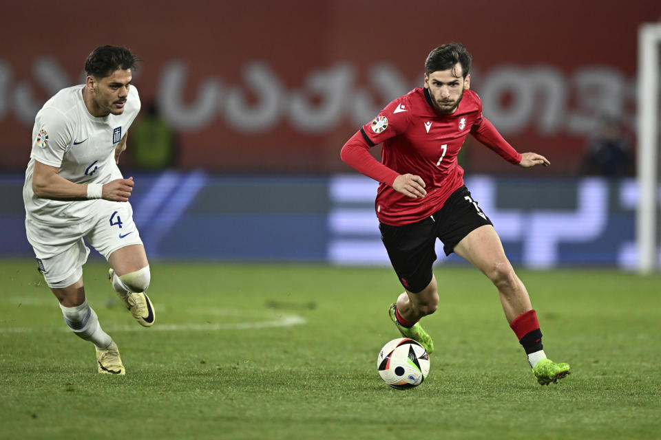 Georgia's Khvicha Kvaratskhelia, right, controls the ball as Greece's Konstantinos Mavropanos tries to stop him during the Euro 2024 qualifying play-off soccer match between Georgia and Greece at the Boris Paichadze National Stadium in Tbilisi, Georgia, Tuesday, March 26, 2024. (AP Photo/Tamuna Kulumbegashvili)