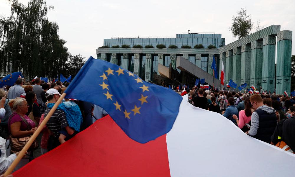 EU and Polish flags are waved during a protest against the supreme court legislation in Warsaw on Saturday.