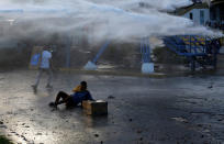 <p>An opposition party supporter lies on the ground after being hit by a water cannon while clashing during a rally against President Nicolas Maduro in Caracas, Venezuela, May 18, 2017. (Marco Bello/Reuters) </p>