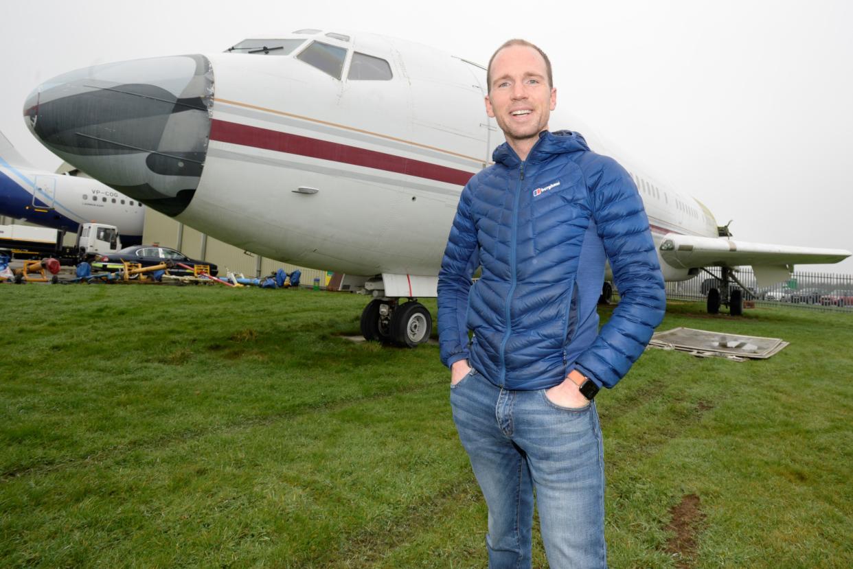 Johnny Palmer, with the 727 in 2021,  is wearing a blue jacket and jeans.