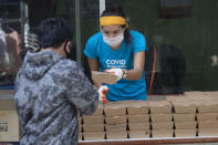 Founder of COVID Thailand Aid, Natalie Bin Narkprasert gives food to people at the railway-side community in Bangkok, Thailand Wednesday, June 10, 2020. Narkprasert, who runs a business in Paris, was stranded in her homeland by a flight ban, so she decided to use her skills to organize the network of volunteers, including Michelin-starred chefs, to help those in her homeland whose incomes were most affected by the pandemic restrictions. (AP Photo/Sakchai Lalit)