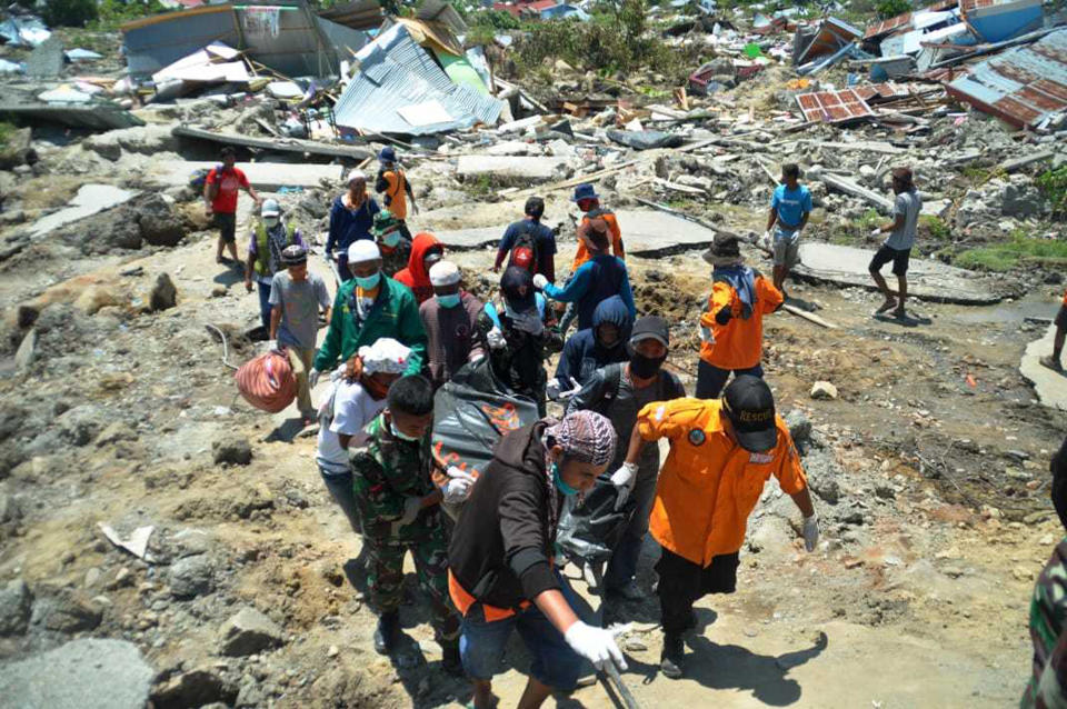 Indonesian rescue team carry the body of a victim in a major earthquake and tsunami in Palu, Central Sulawesi, Indonesia, Monday, Oct. 1, 2018. A mass burial of earthquake and tsunami victims was being prepared in a hard-hit city Monday as the need for heavy equipment to dig for survivors of the disaster that struck a central Indonesian island three days ago grows desperate.(AP Photo/Rifki)