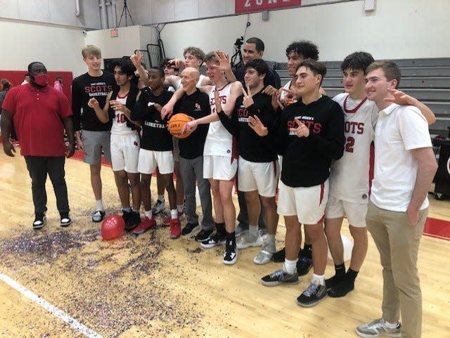 St. Andrew's coach John O'Connell (holding basketball) and his team pose for a postgame photo to commemorate O'Connell's 700th career victory.