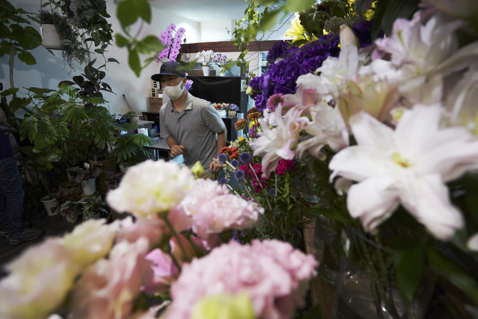 Shinichiro Hirano walks through his Sun Flower Shop in Tokyo on June 22, 2020. When Japanese officials asked people to stay home in March, the shop was allowed to stay open. The store, not far from the Athletes Village built for the Tokyo Olympics, had been expecting a boom, only to see it fizzle when the games were postponed. (AP Photo/Eugene Hoshiko)