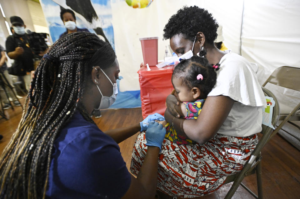 A nurse vaccinates a toddler being held by her mother.