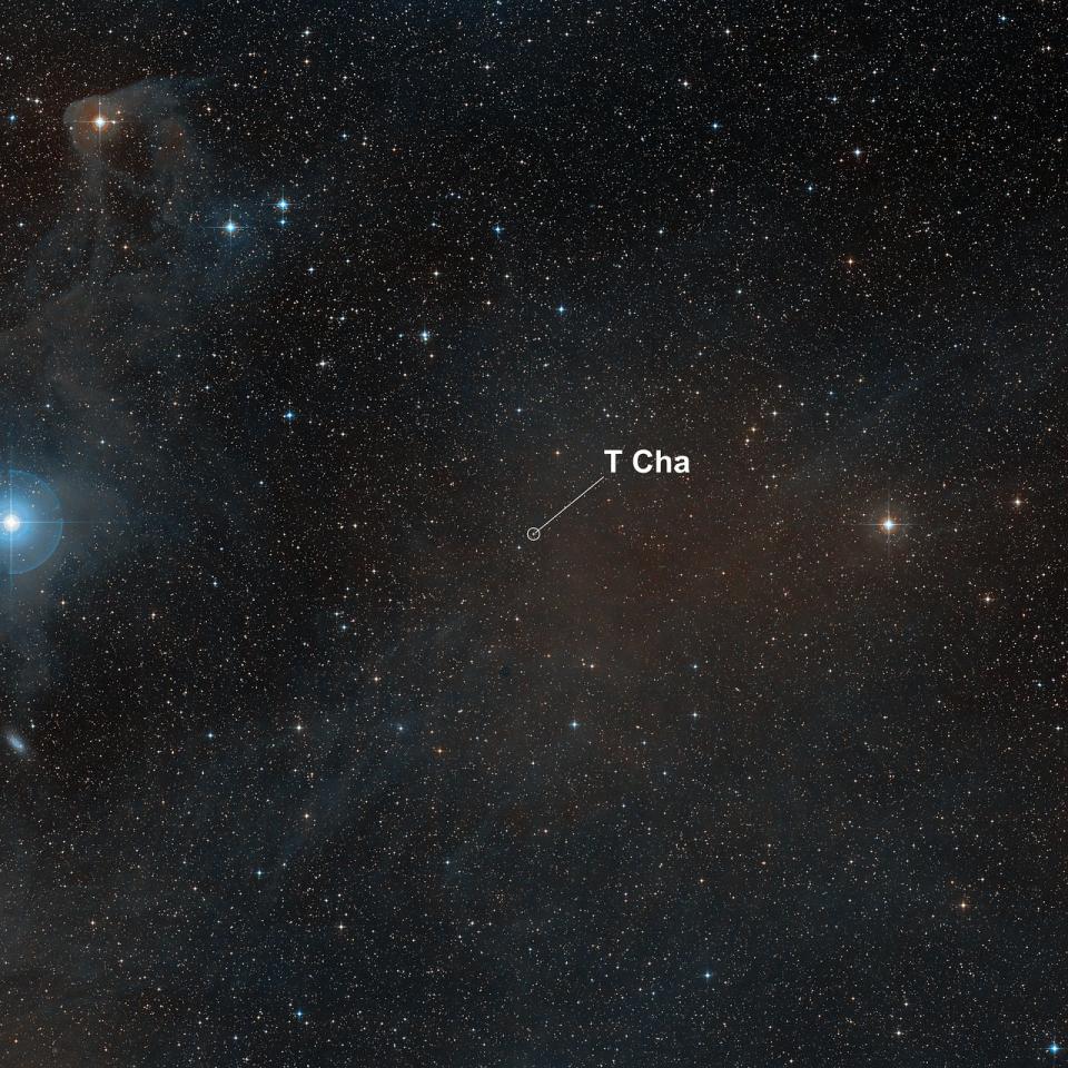 A view of a patch of starry sky with an area containing an arrow indicating the location of T Cha.