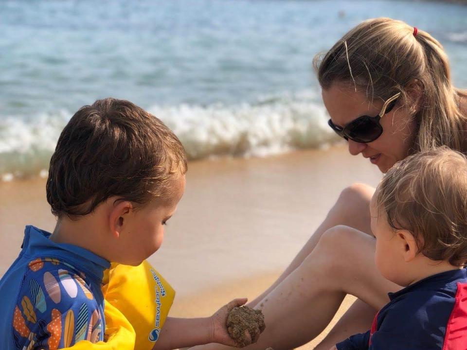 Woman on beach in Spain with two small chiildren.