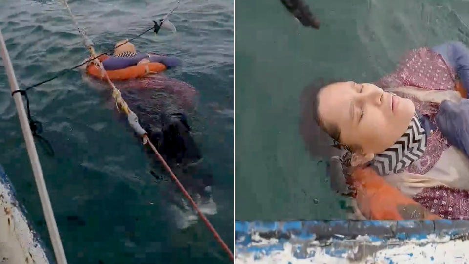 A woman is seen floating in the water, fully clothes with a floatation device around her as she is rescued.