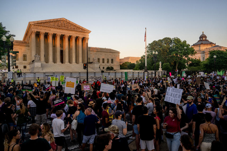 A large crowd in front of the courthouse, with many holding up signs, including "Abortion is health care" and "Amend the Constitution"