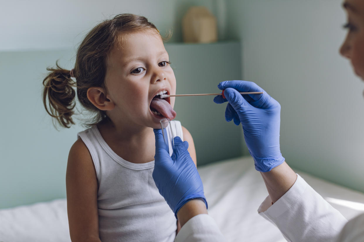 Nurse performing a mouth swab test on a little child.