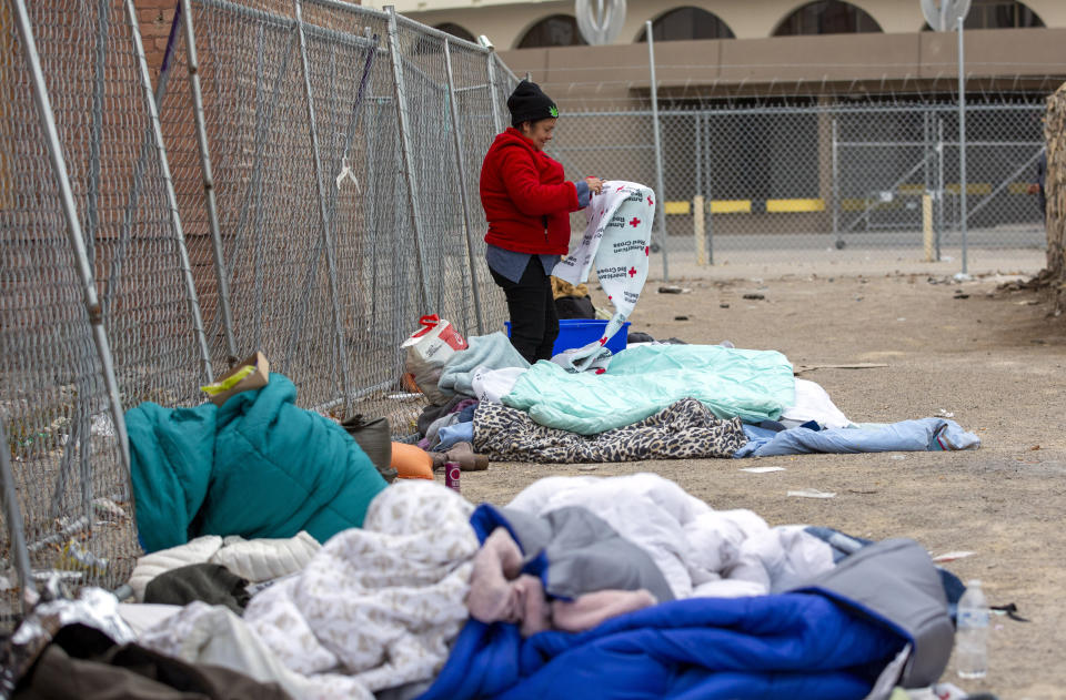 A migrant unfolds a donated blanket to prepare to spend another day on a street in downtown El Paso, Texas, Sunday, Dec. 18, 2022. Texas border cities were preparing Sunday for a surge of as many as 5,000 new migrants a day across the U.S.-Mexico border as pandemic-era immigration restrictions expire this week, setting in motion plans for providing emergency housing, food and other essentials. (AP Photo/Andres Leighton)