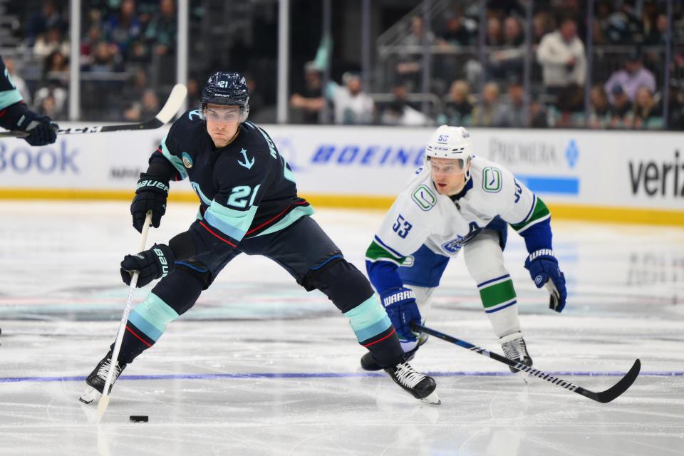 Feb 22, 2024; Seattle, Washington, USA; Seattle Kraken center Alex Wennberg (21) plays the puck while defended by Vancouver Canucks center Teddy Blueger (53) during the second period at Climate Pledge Arena.
