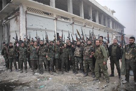 Syrian army soldiers loyal to Syria's President Bashar al-Assad pose for a photograph with their weapons in the Aleppo town of Naqaren, after claiming to have regained control of the town, January 14, 2014. REUTERS/George Ourfalian