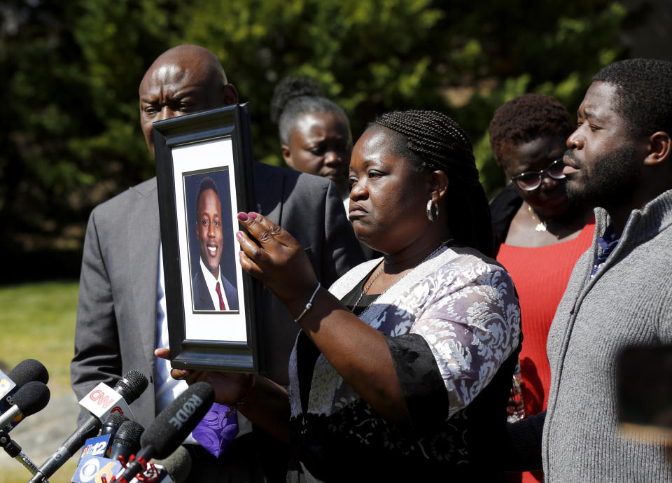 Caroline Ouko, mother of Irvo Otieno, holds a portrait of her son with attorney Ben Crump, left, and her older son, Leon Ochieng at the Dinwiddie Courthouse in Dinwiddie, Va., on Thursday, March 16, 2023. She said Otieno, who died in a state mental hospital March 6, was “brilliant and creative and bright.” (Daniel Sangjib Min/Richmond Times-Dispatch via AP)