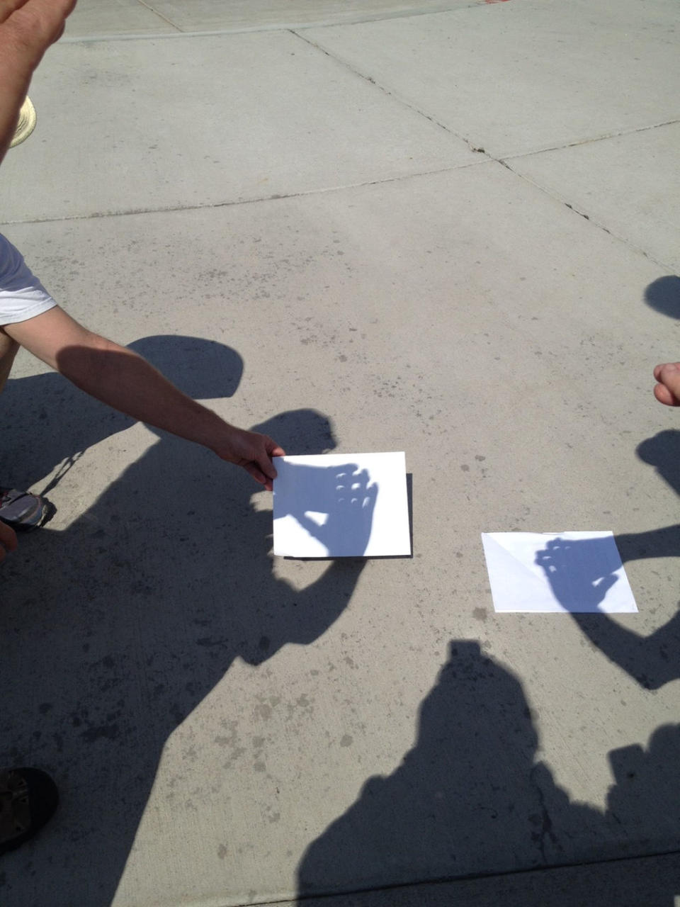 During total eclipse, participants use their hands to observe crescent shapes on the ground. <cite>Leonard David</cite>