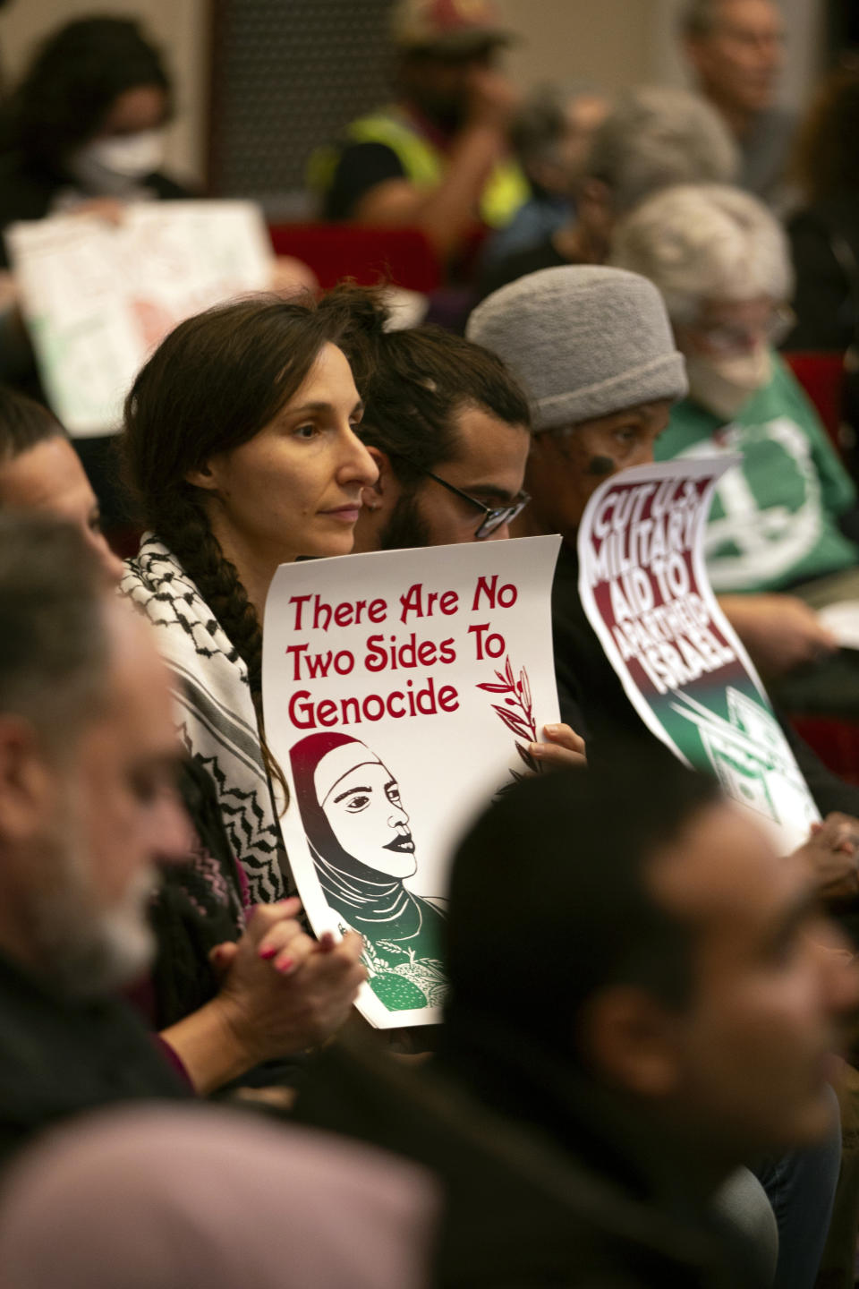 Audience members hold signs expressing their opinions on a resolution calling for an immediate cease-fire in Gaza, Monday, Nov. 27, 2023, in Oakland, Calif. (AP Photo/D. Ross Cameron)