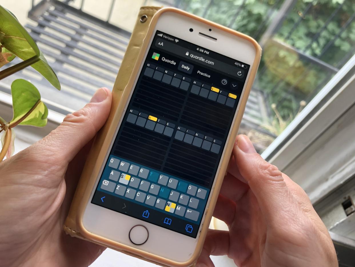 close on a woman's hands as she plays 'Quordle' on a smartphone